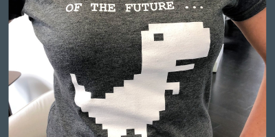 A person wearing a t-shrt with a pixellated dinosaur and the words "don't be a dinosaur of the future...move to the cloud"